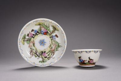 A Meissen cup with a saucer, painted with scenes from the dwarf riding school